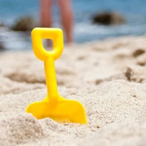 Bright yellow shovel in sandy beach setting, perfect summer fun imagery.